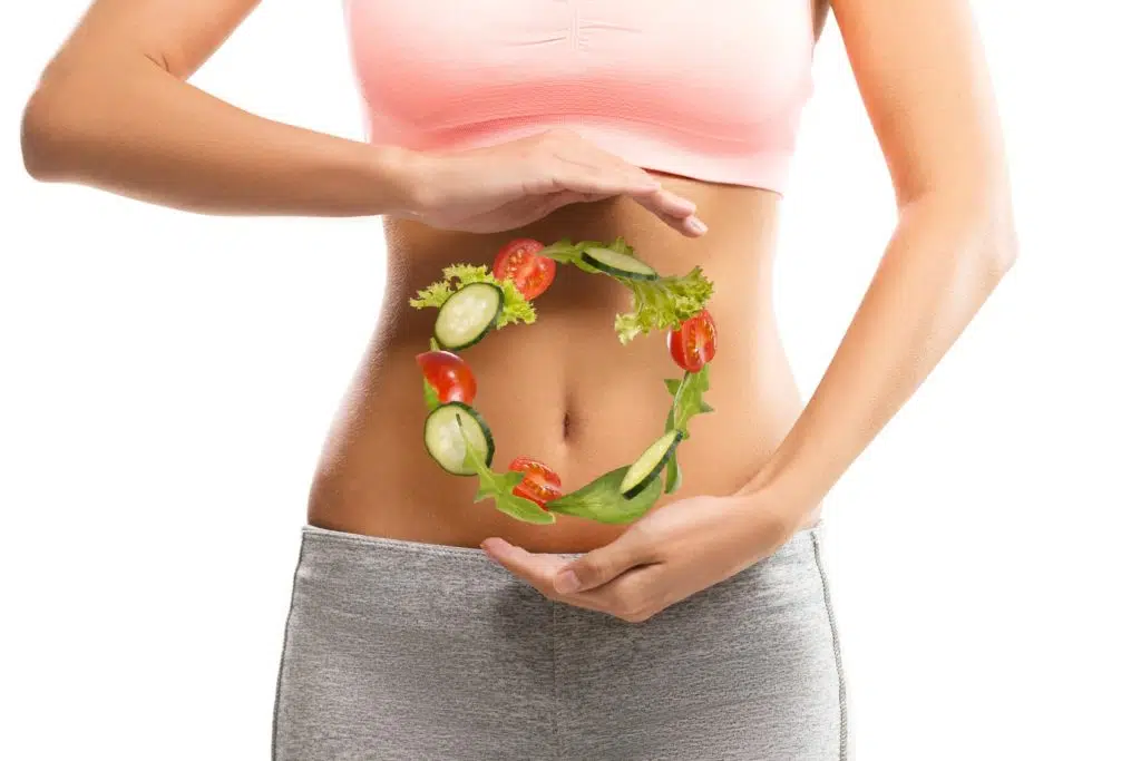 Fit, young woman holding a circle made out of vegetables over her abdomen