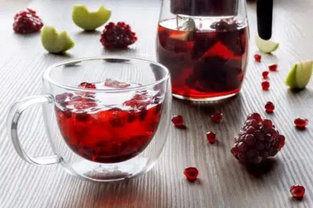 thermal glass cup with ice and pomegranate tea with apple