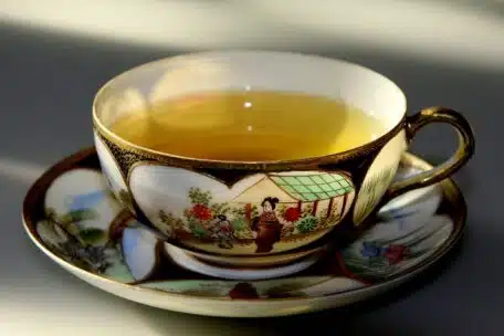 Filiżanka ze spodeczkiem z chińskiej porcelany pełna zielonej herbaty